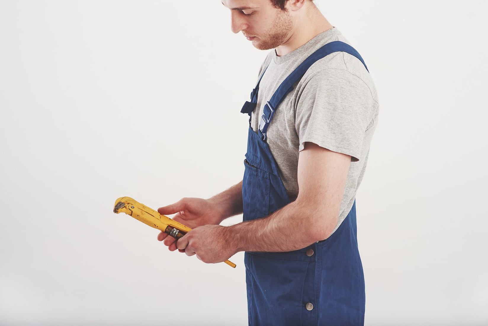 Instalator trzyma żółty klucz do rur